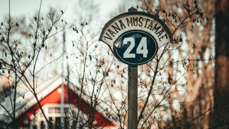 a street sign with a house in the background