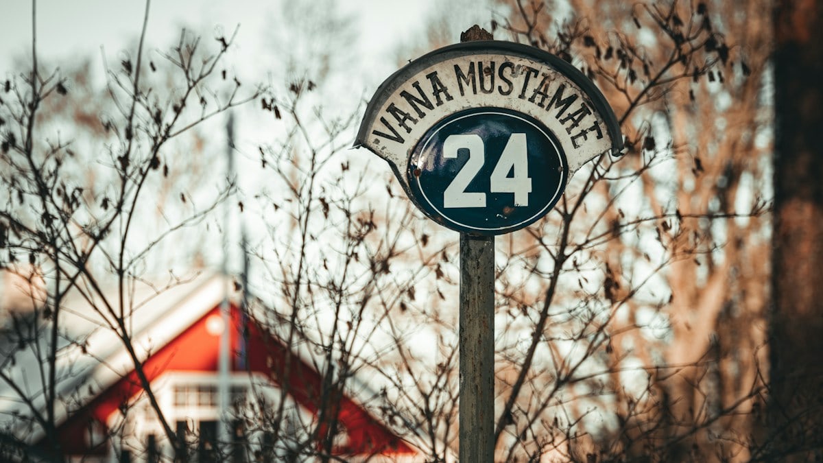 a street sign with a house in the background